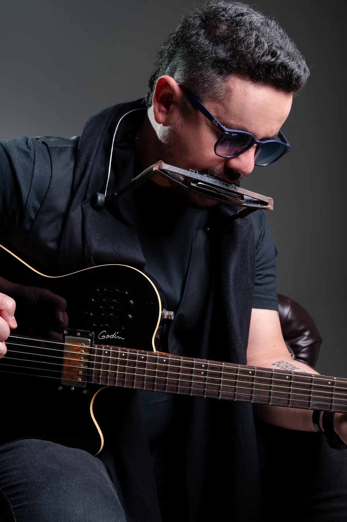 Roy debruçado sobre a guitarra, tocando gaita no suporte