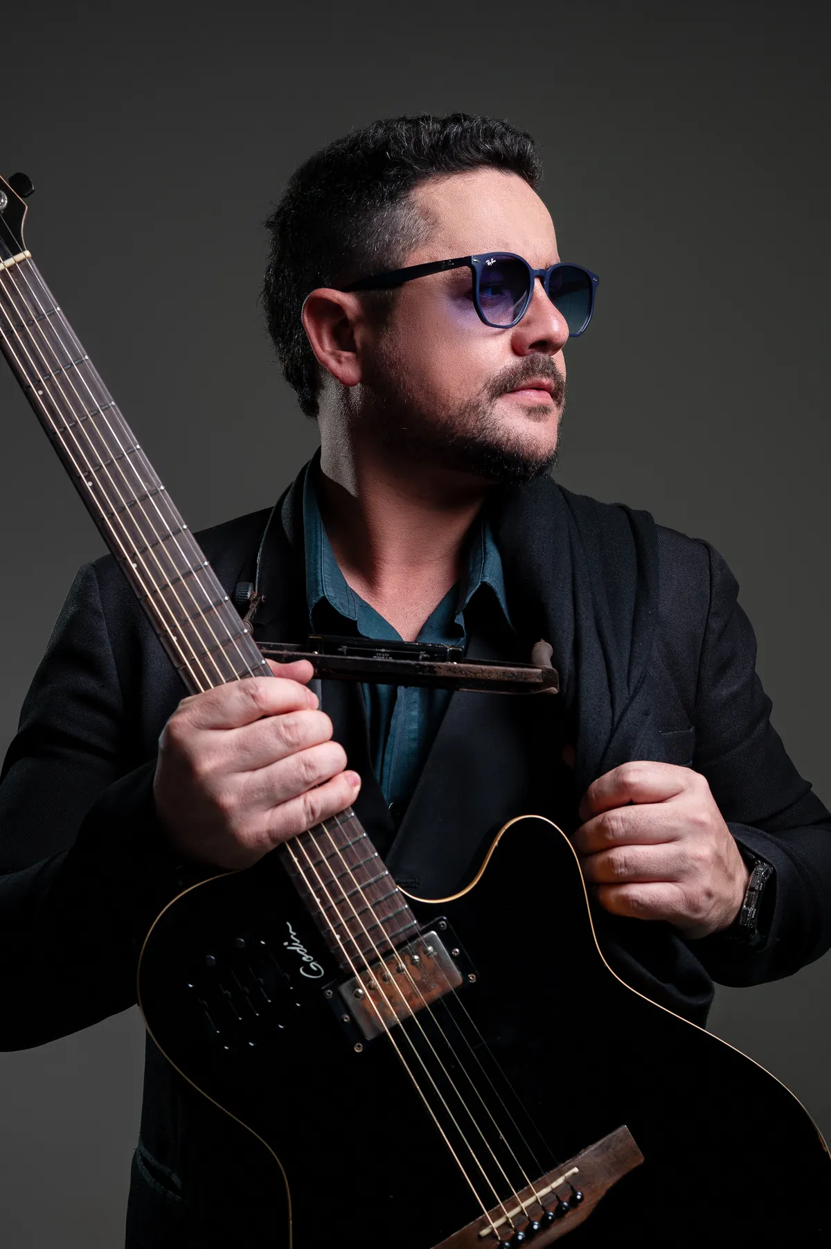 Mãos de Roy na guitarra, com a gaita presa no pescoço